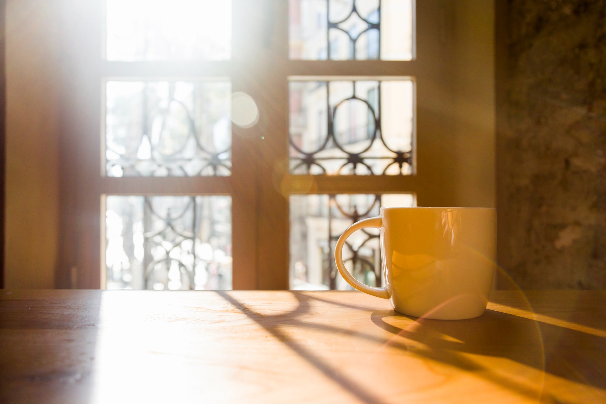 Yellow mug on a wooden surface with sunlight filtering through a window